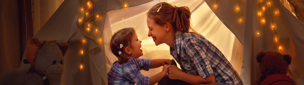 happy mother and daughter playing at home in tent